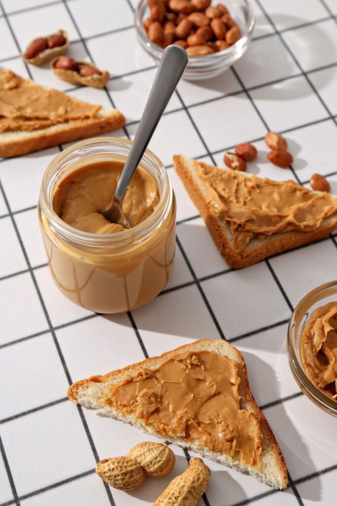 Peanut butter in a jar with toast and raw peanuts