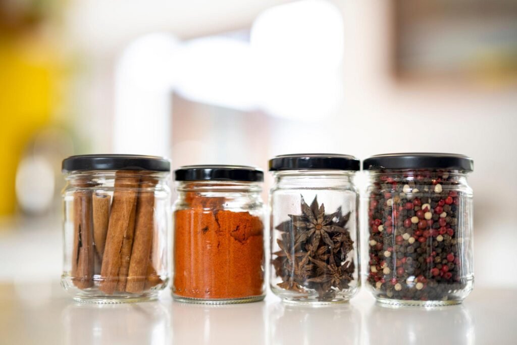 Glass spice jars with cinnamon, paprika, star anise, and peppercorns